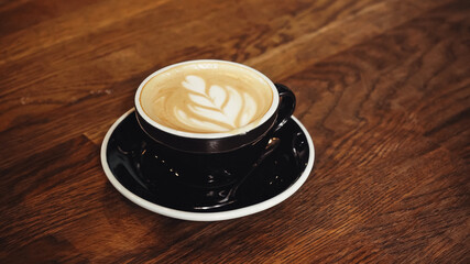 cup of delicious cappuccino with latte art on table