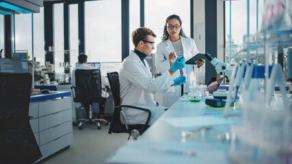 Modern Medical Research Laboratory: Shot of Two Young Scientists Using Pipette, Digital Tablet,...
