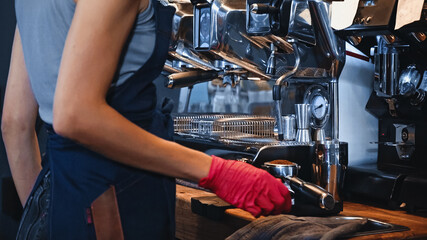 Fototapeta na wymiar cropped view of barista near portafilter with ground coffee in coffee shop