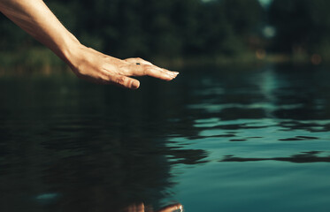 Beautiful woman's palm strokes the water of the lake