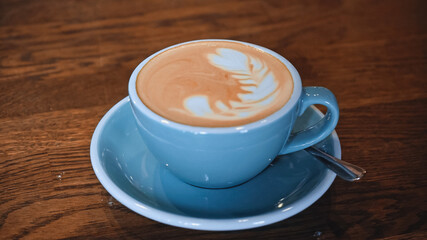 blue cup of delicious cappuccino with latte art on table