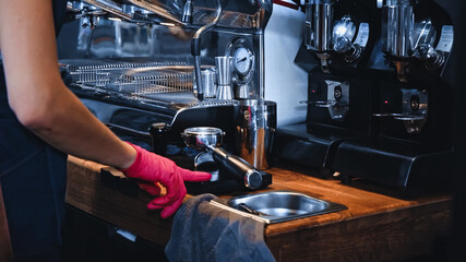cropped view of barista pointing with finger at clean portafilter near professional coffee machine