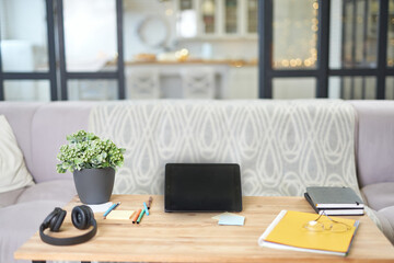 Modern workplace. Still life view of a home office room with digital tablet, notebook, wireless headphones and sofa