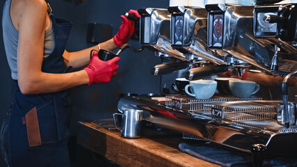 cropped view of barista in latex gloves holding pitcher near steam wand