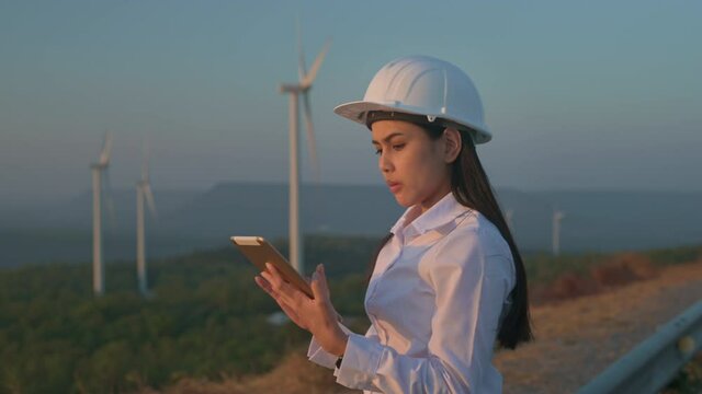 a woman engineer is wearing a protective helmet on her head, using tablet Analytics engineering data.