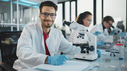 Medical Science Laboratory: Handsome Latin Scientist Analysing Samples and Uses Microscope, Looking...