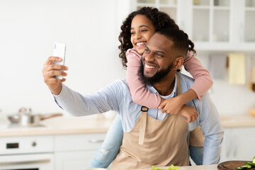 Cheerful african father taking selfie with cute daughter