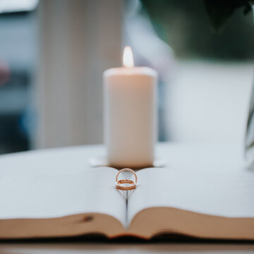 Weddingrings on a Bilbe with an white candle in the Backgraound