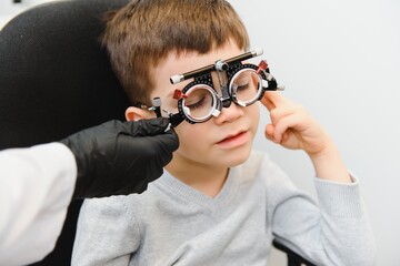 Cheerful child boy in glasses checks eye vision pediatric ophthalmologist.