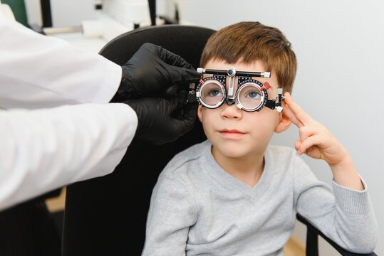 Cheerful child boy in glasses checks eye vision pediatric ophthalmologist.