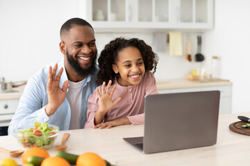 Black man and girl having videocall using laptop waving hands