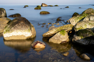 Fototapeta na wymiar Big boulders reflecting in smooth ocean surface on a sunny spring day
