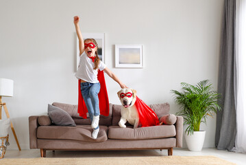 Happy kid and dog in Superhero outfits having fun at home