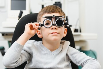 Cheerful child boy in glasses checks eye vision pediatric ophthalmologist.
