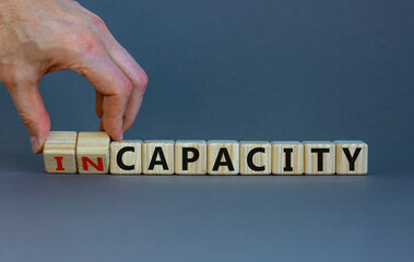 Capacity or incapacity symbol. Businessman turns wooden cubes and changes the word 'incapacity' to 'capacity'. Beautiful grey background. Business and capacity or incapacity concept. Copy space.