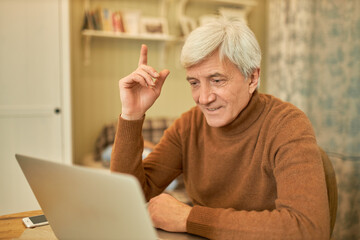 Indoor shot of successful middle aged businessman with gray hair raising fore finger as sign of...