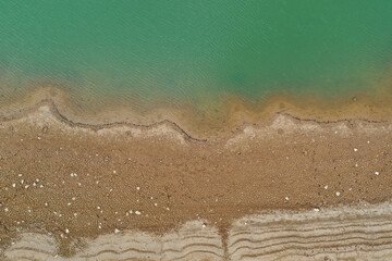 Aerial top view pattern of clear river water and sand on the river bank