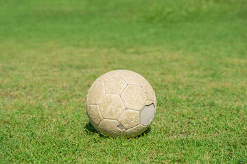 Plakat Old soccer ball on green grass of soccer field.