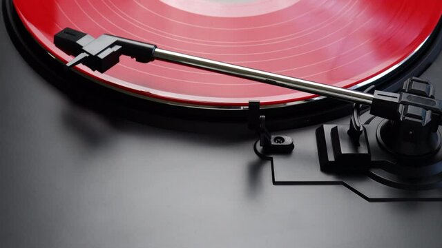 Removing red vinyl record from a turntable - close up of tonearm moving to it's default position - Removing the red LP from a turntable
