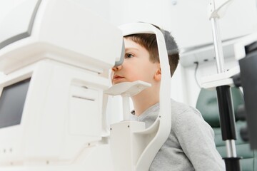 Optometry concept. Female optometrist optician doctor examines eyesight of child boy in eye...