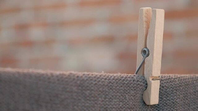 One wooden clothespin holding clothes on a rope. Drying on a wire, gently moved by the wind, housework concept