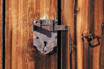 Handmade old lock on a weathered wooden door.
