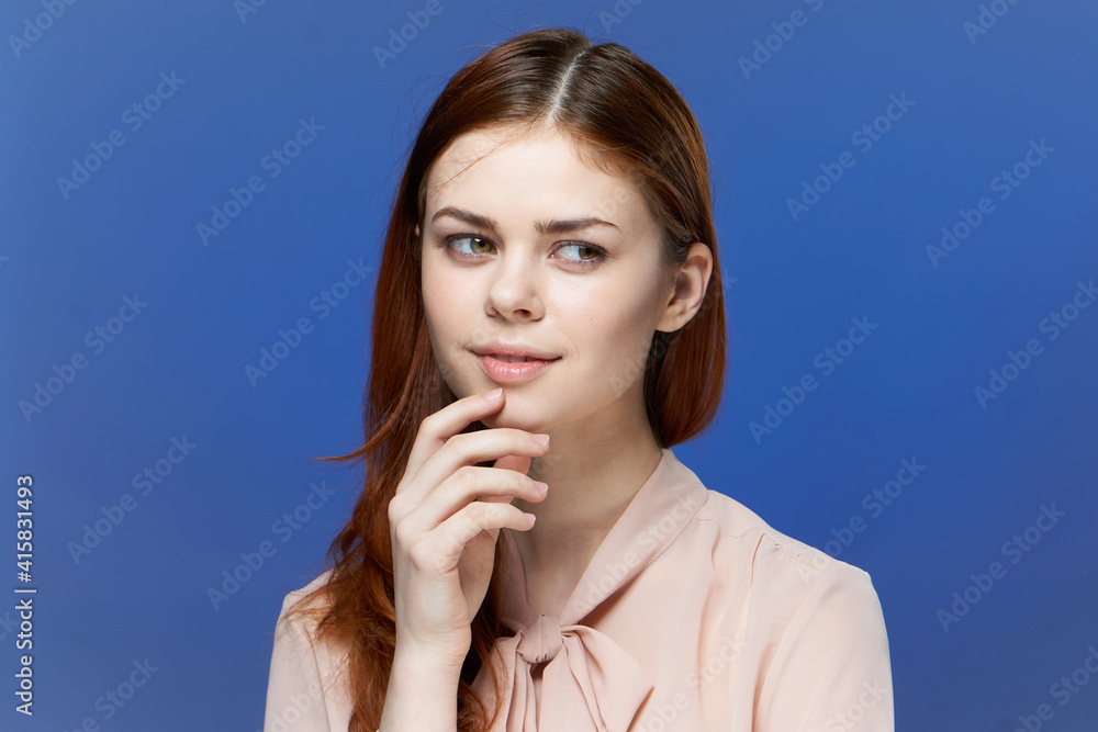 Wall mural pretty woman in pink shirt hand near face blue background