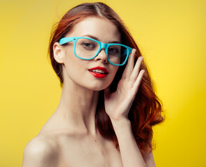 woman with bare shoulders blue glasses red hair cropped view