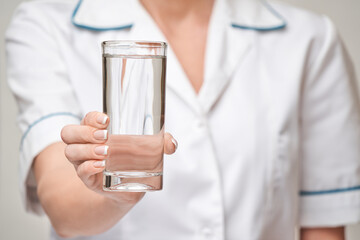 Healthy eating or lifestyle concept - female woman doctor holding and a glass of clear fresh water