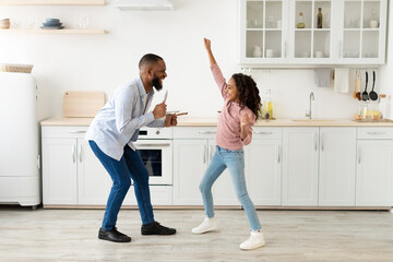 Black father and daughter dancing in the kitchen together