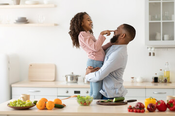 Black dad and daughter playing in the kitchen