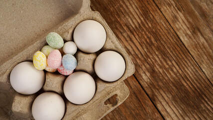 Chicken eggs in a cardboard tray and Easter decor on a wooden background., Rural Style