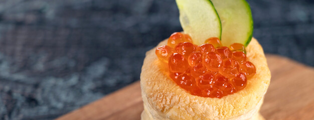 Banner with tartlets, red caviar, cucumber on a black table. Appetizer with red caviar. Delicious and healthy snack.