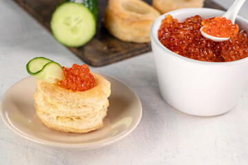 Tartlets, red caviar, cucumber on a white table. Recipe for making an appetizer with red caviar. Cooking process.
