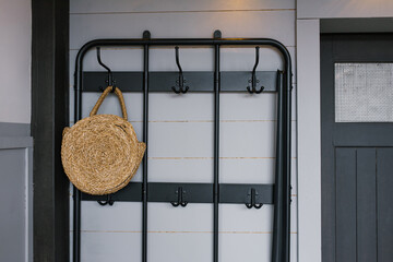 A wicker bag hangs on a hanger near the front door in the interior of a Scandinavian house