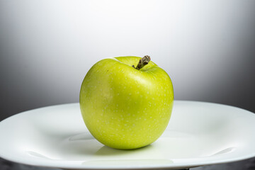 a whole green apple on a white plate