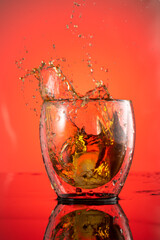 splash in a glass of whiskey from falling ice on a red background