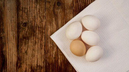 Close up of fresh chicken eggs on nature wooden table with copy space. White eggs and one brown