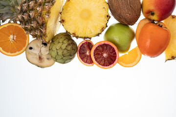 Selection of sliced fresh fruits with kiwis, pineapple, blood orange on white background with free...
