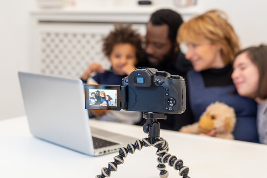 detail of a camcorder in operation while filming a mixed-race family, parents and children who use modern technology to film themselves and use it for their blog and social network, vlogger family