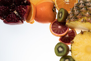 Selection of sliced fresh fruits with kiwis, pineapple, blood orange on white background with free...