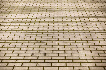 Image of a cobbled road in an urban environment. Paving stones on a footpath or car park in the city. Paving stone pattern in perspective. Natural daylight, cloudy weather.