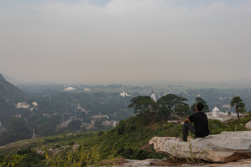 man sitting isolated at rock and watching amazing landscape