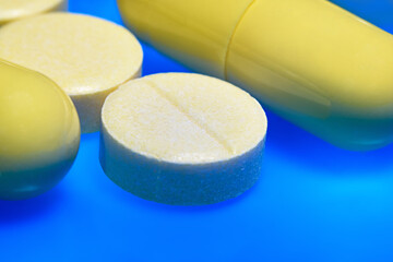 yellow round pill and capsules close-up. macro. blue background