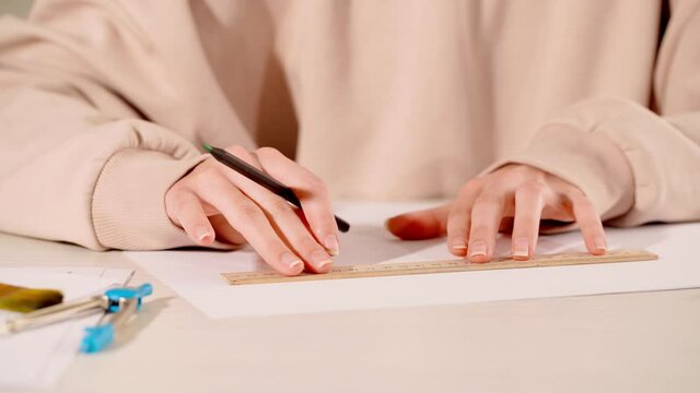 cropped view of woman using ruler to draw lines on paper
