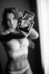 Sexy young woman in lingerie taking a selfie on phone