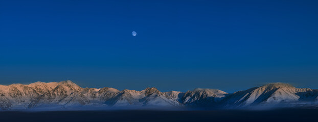 blurred view of plain at root of snow-covered mountains at sunny day