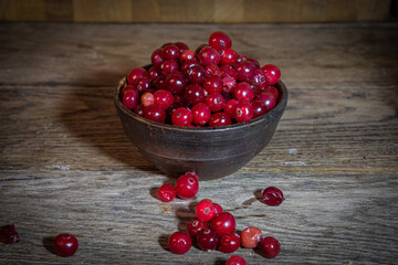 Ripe red viburnum in a ceramic dish on a wooden table.