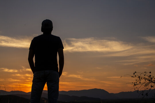 Hombre a contraluz en un atardecer naranja
