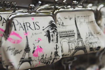 Paris themed kitschy change purses hanging on rack with eiffel tower, arc di triomphe and pink lips.